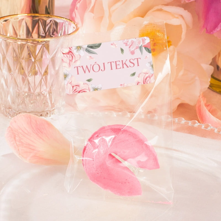 Ciasteczko z wróżbą w różowym kolorze z personalizowaną etykietą z motywem biało-różowych kwiatów i zielonych listków
