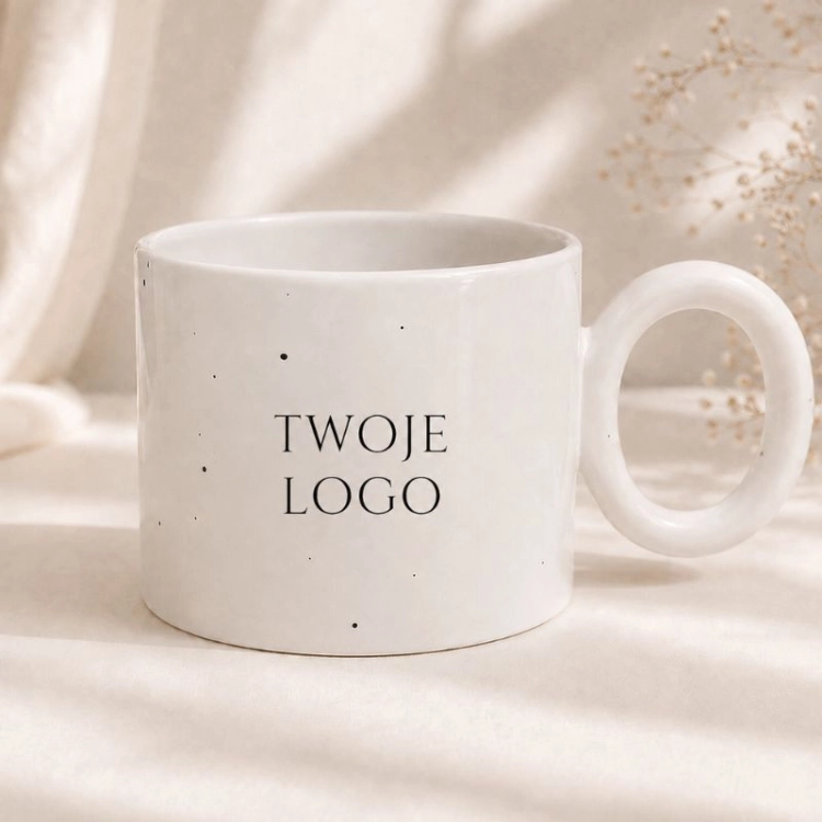Biały kubek nakrapiany z logo firmy to elegancki gadżet reklamowy do biura i na wydarzenia firmowe.