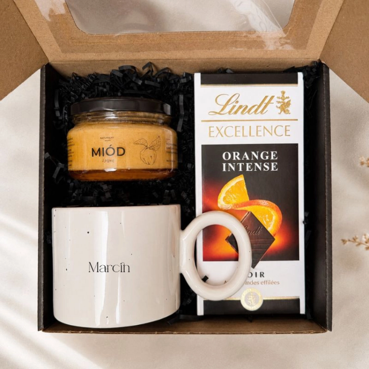 Personalizowany zestaw prezentowy zawiera duży kubek z imieniem, czekoladę Lindt i miód.