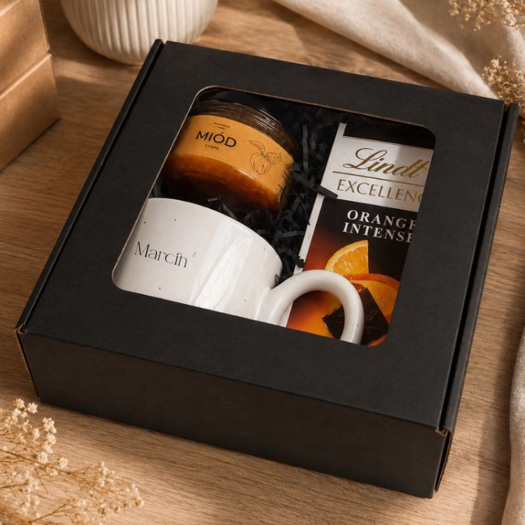 Zestaw z kubkiem, czekoladą Lindt Orange Intense i miodem znajduje się w czarnym pudełku.