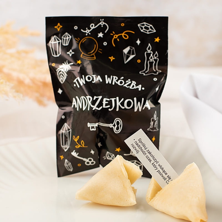 Ciasteczko z wróżbą na andrzejki w czarnym opakowaniu z napisem Twoja Wróżba Andrzejkowa.