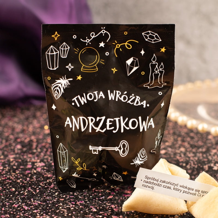 Ciasteczka z wróżbą w czarnym opakowaniu z ozdobnymi grafikami andrzejkowymi.